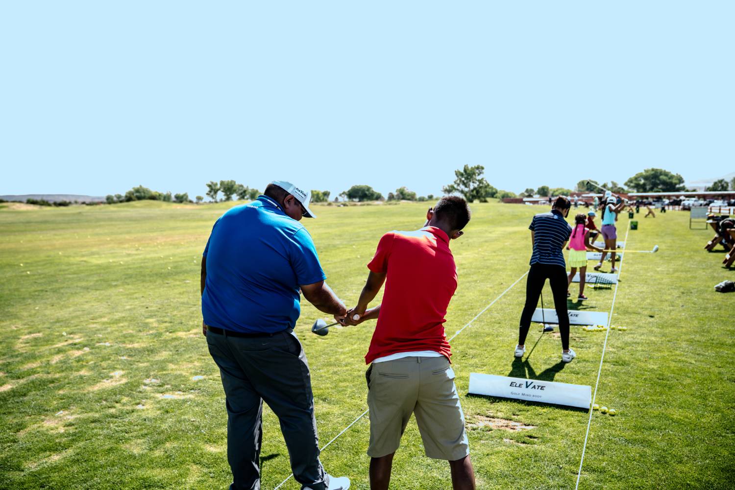 Golf instructor helping student with follow-through